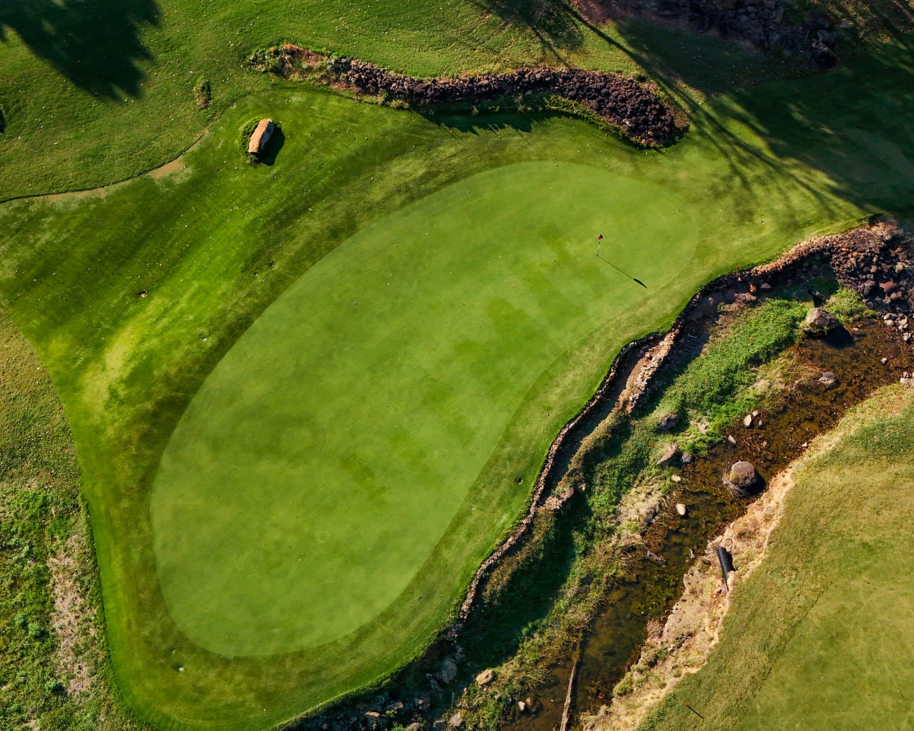 Aerial view of golf green, rocks, and water